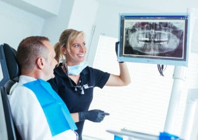 Digitales Röntgen Implatologin bespricht Röntgenbild mit Implantat mit Patient